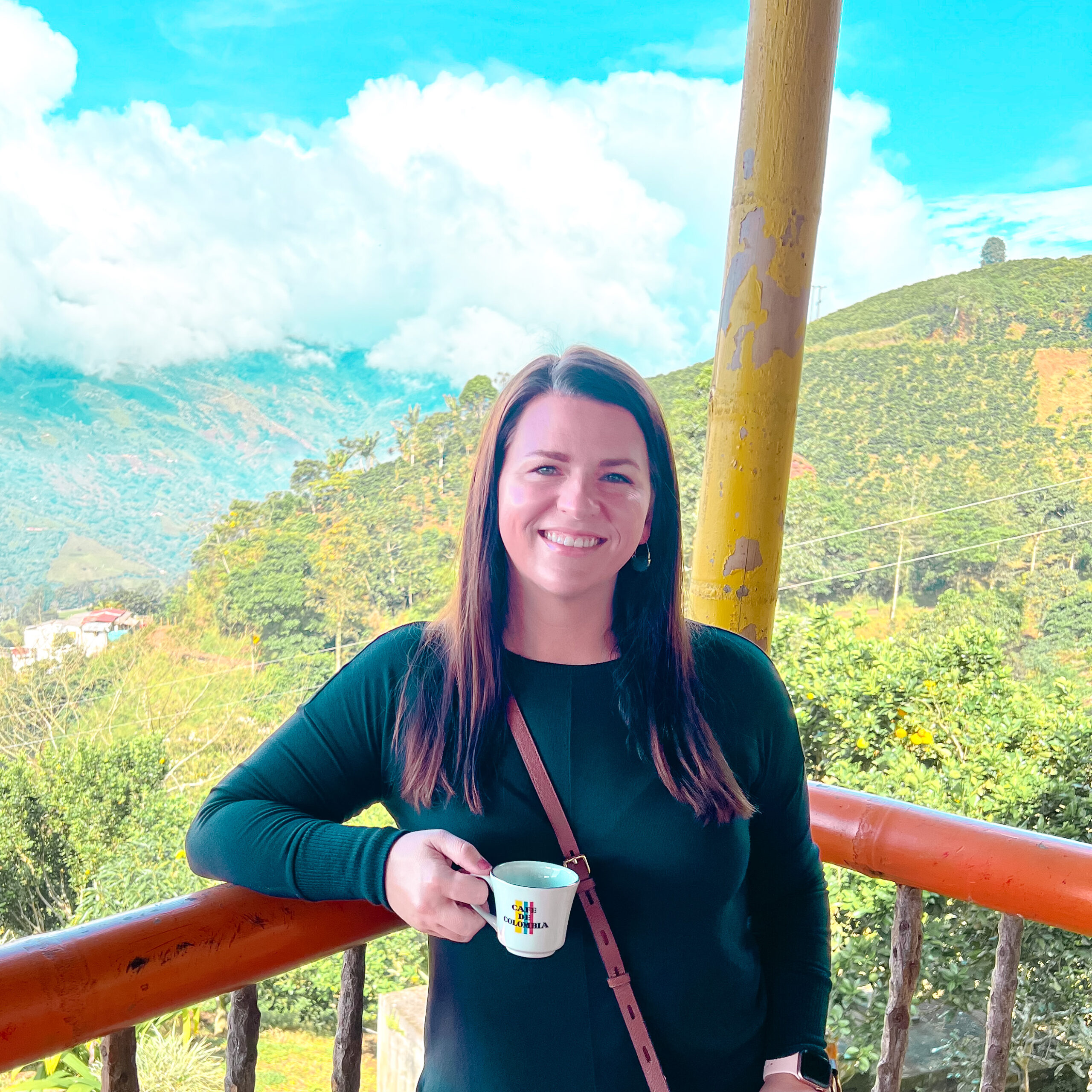 Sra Cruz Spanish Teacher holding Cafe de Colombia cup with a backdrop of Colombian mountains